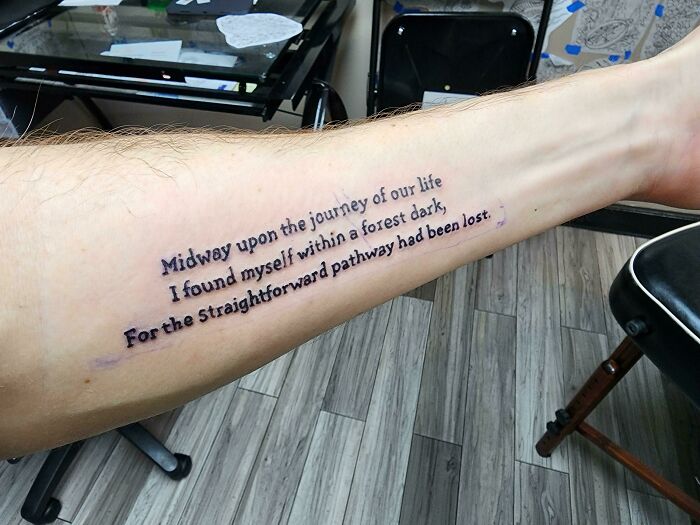 Forearm with a creative word tattoo featuring a literary quote in elegant script.