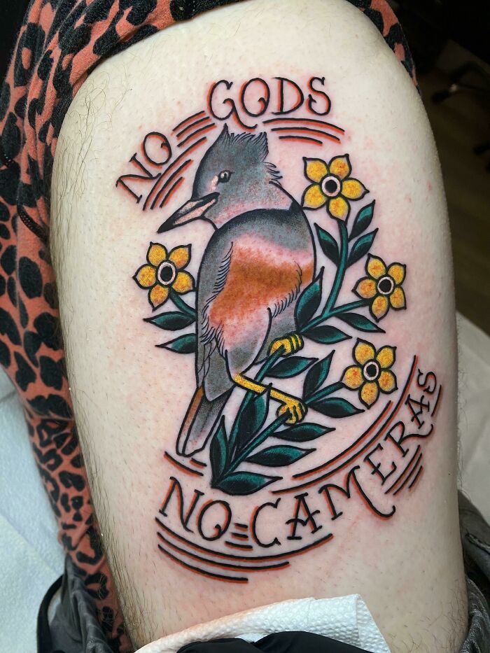 Bird and flowers tattoo with "No Gods No Cameras" text, a creative ink idea for new word tattoos.