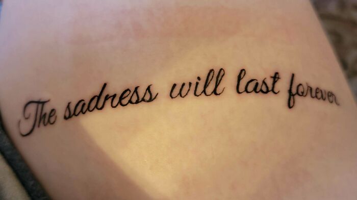 Close-up of a cursive script word tattoo with a misspelling on skin.