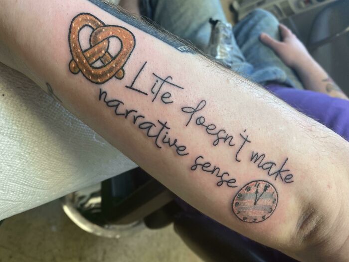 Creative word tattoo on an arm featuring a pretzel and clock motif.