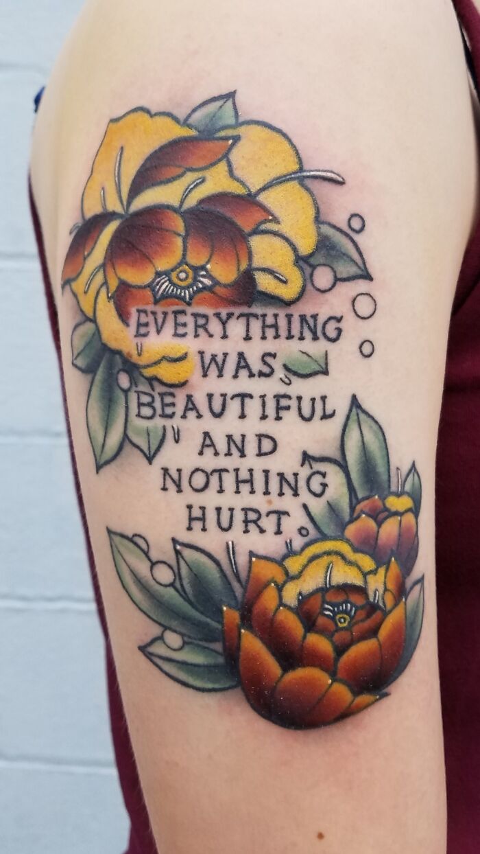 Colorful floral tattoo with inspirational words on an arm.