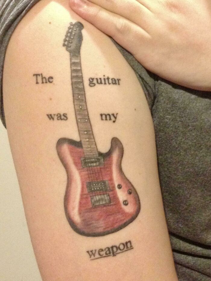 Word tattoo of a guitar on an arm with text: "The guitar was my weapon."