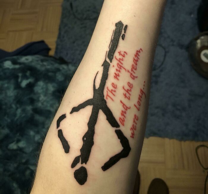 Creative word tattoo on forearm in black and red ink, featuring a quote.