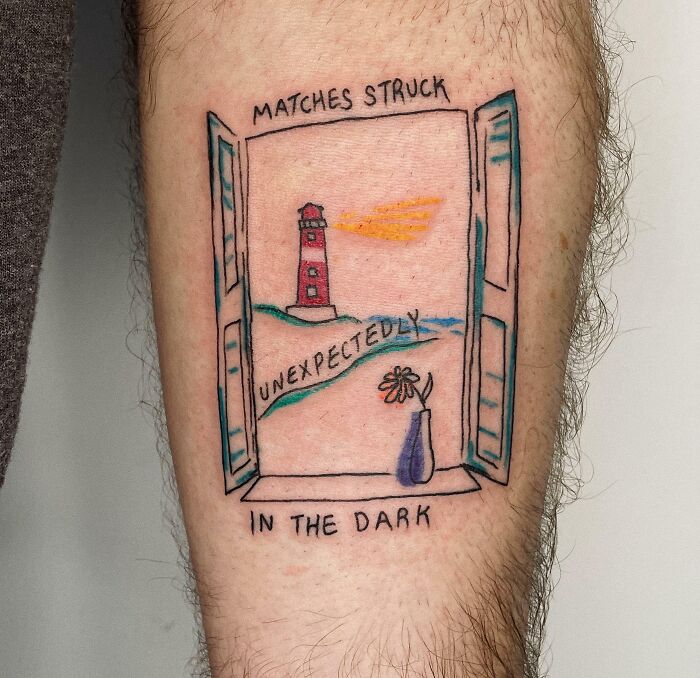 Word tattoo of a lighthouse and flower vase within a window, featuring the phrase "Matches struck unexpectedly in the dark."