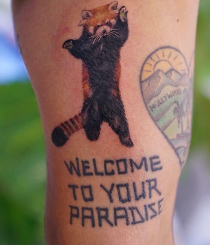 Red panda tattoo with "Welcome to Your Paradise" text on arm, perfect for new ink ideas.