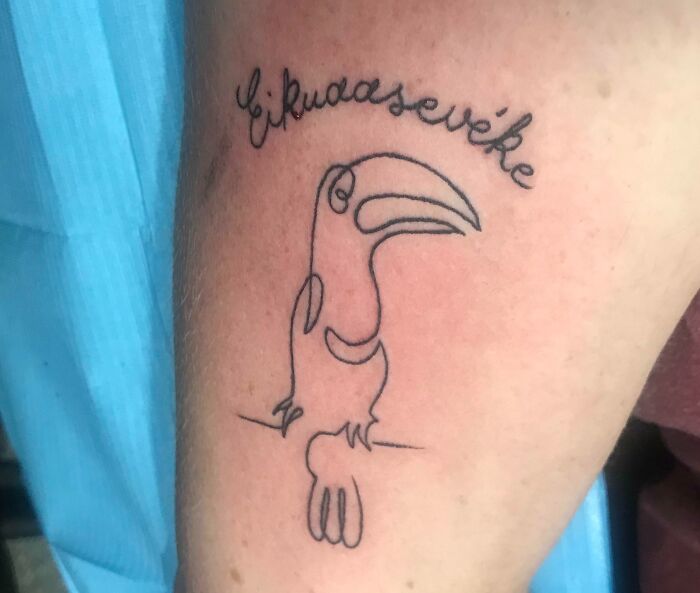 Line tattoo of a toucan and text on a person's arm, showcasing a creative word tattoo idea.