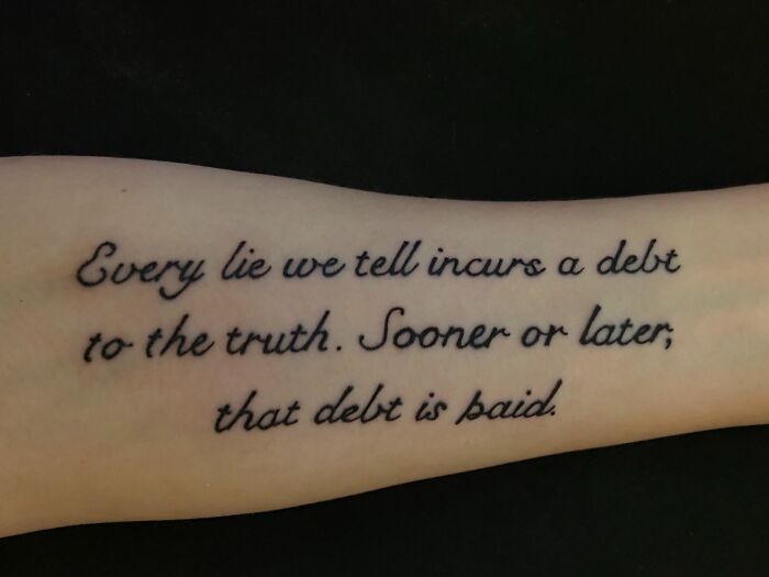 Arm with a meaningful word tattoo about truth and consequences in cursive script.
