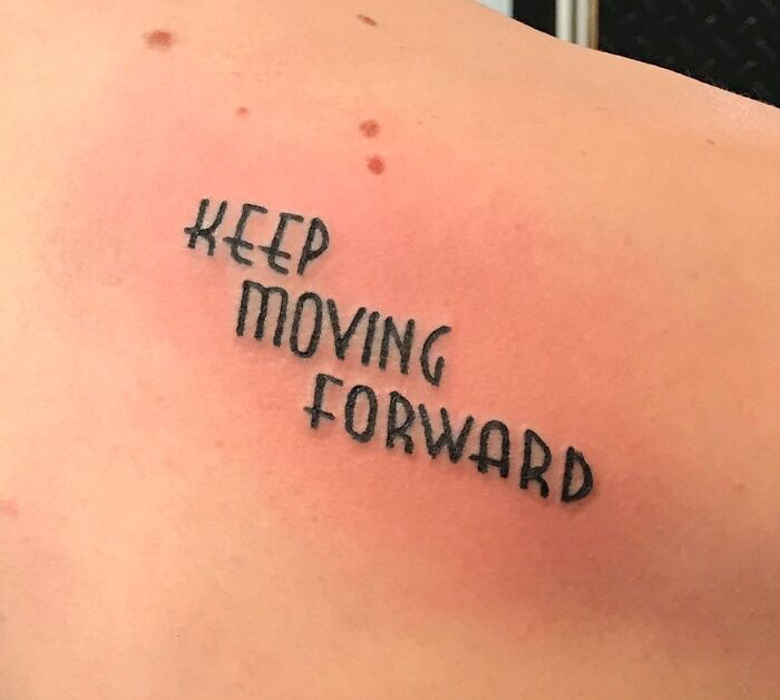 Tattoo of the words "Keep Moving Forward" in black ink on skin, representing creative word tattoo ideas.