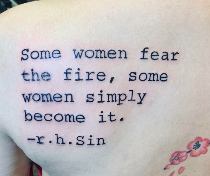 Tattoo with the quote "Some women fear the fire, some women simply become it" by r.h. Sin, with a floral design below.