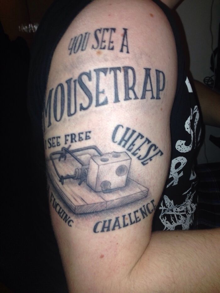 Creative word tattoo on an arm featuring a mousetrap and cheese with an inspirational message.