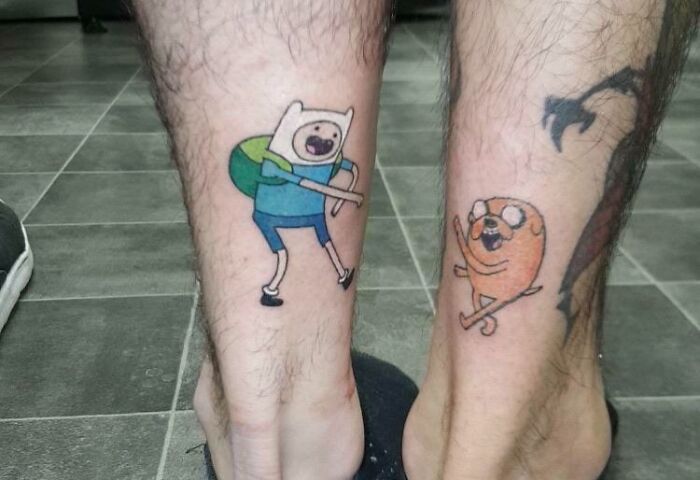 Cartoon character tattoos on legs, symbolizing friendship.