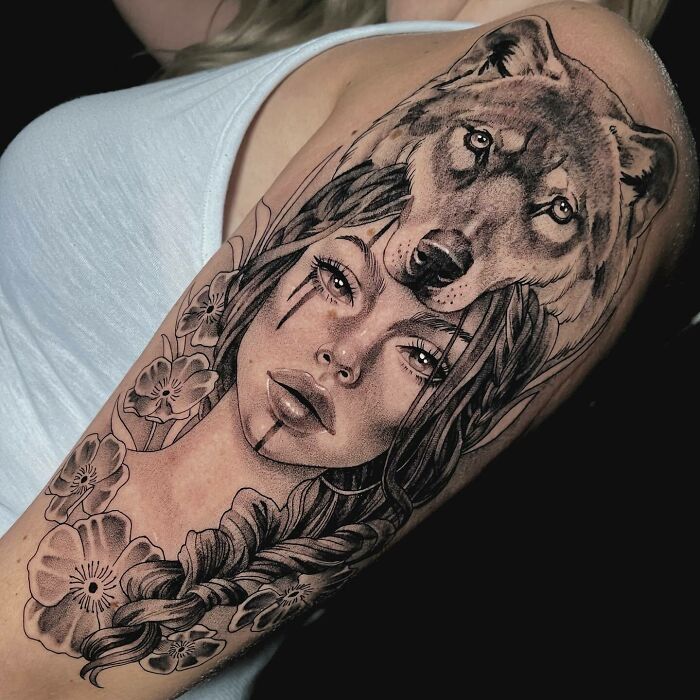 Nature tattoo featuring a woman's face with a wolf headdress and floral details on the arm.