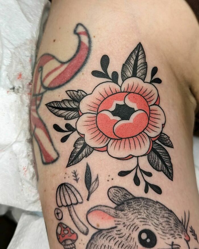 Nature tattoo with a stylized flower, leaves, mushrooms, and a cute animal on the arm.