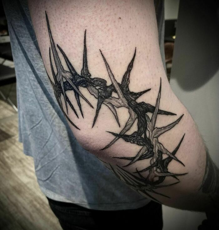 Abstract nature tattoo with thorny design on a person's arm.