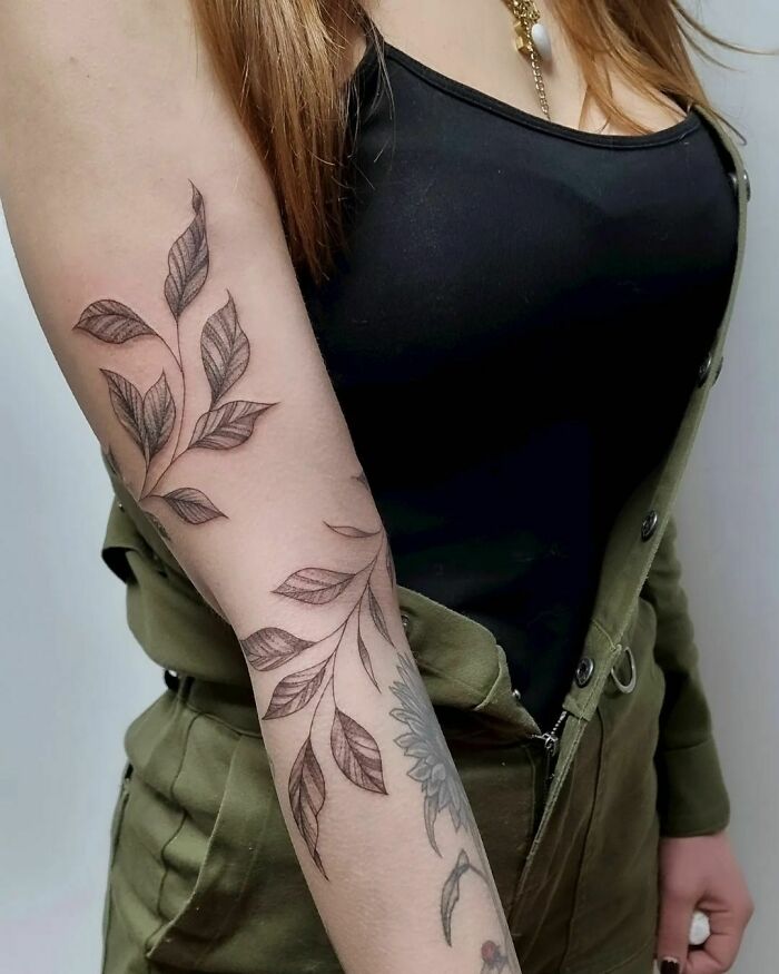 Arm with a nature tattoo featuring intricate leaf design, celebrating the human-earth bond.