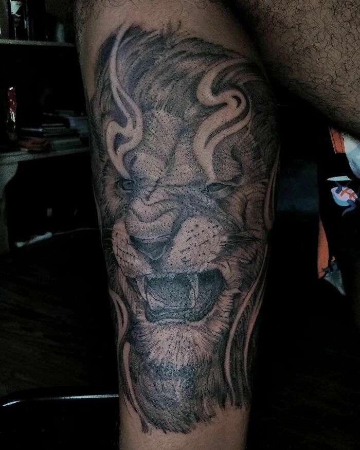 Lion-themed nature tattoo showcasing intricate design on a person's leg.