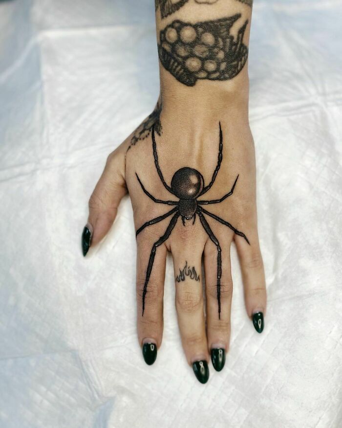 Spider tattoo on hand, showcasing intricate nature design with black ink.
