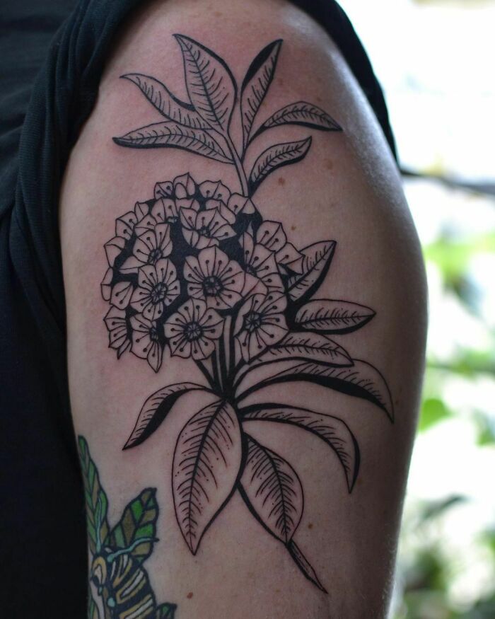Nature tattoo featuring detailed black and grey floral design on upper arm.