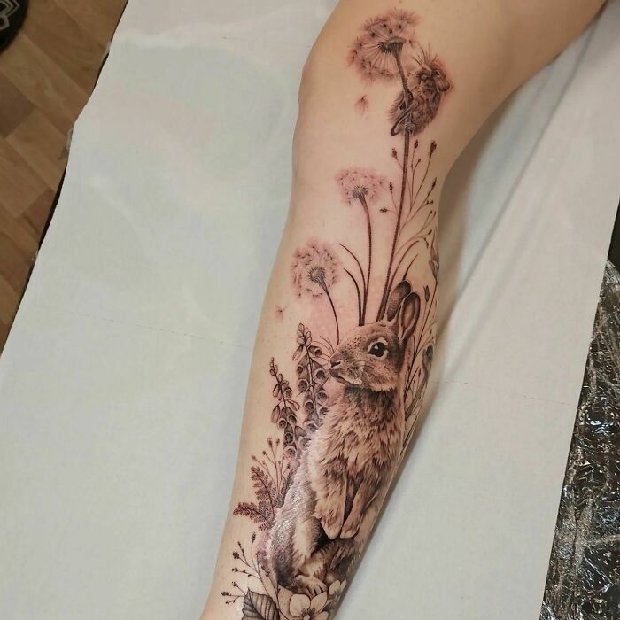 Rabbit and dandelion nature tattoo on a forearm, showcasing detailed wildlife and floral artistry.