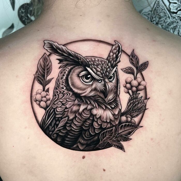 Owl nature tattoo on back, featuring detailed leaves and berries, showcasing human-earth bond.