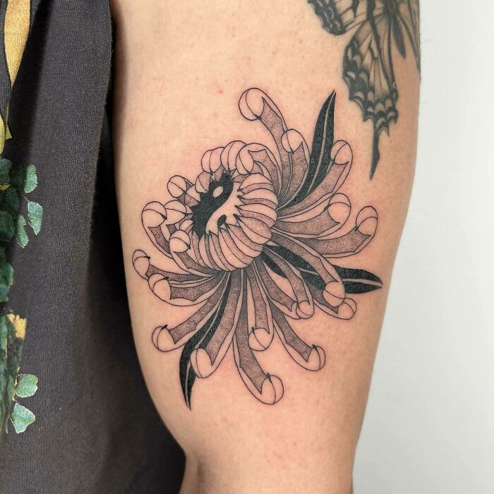 Floral nature tattoo on arm, showcasing intricate black lines and shading for a Mother Earth-inspired design.