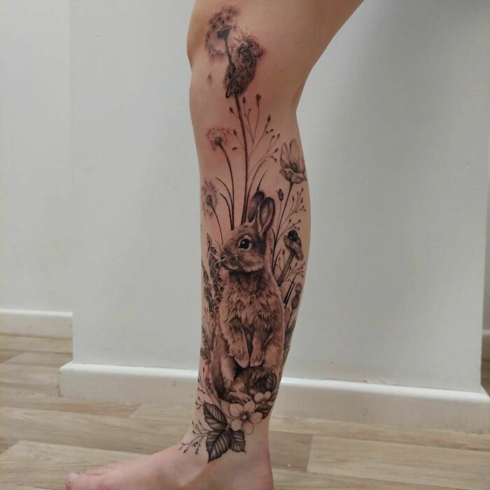 Nature tattoo of a rabbit and flowers on a leg, celebrating the human-earth bond.