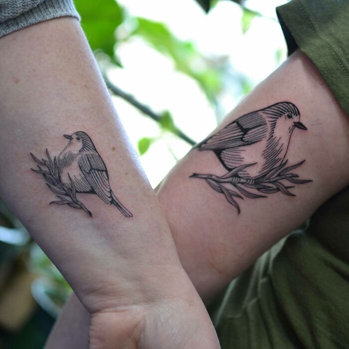 Two nature tattoos featuring birds on branches adorn forearms.