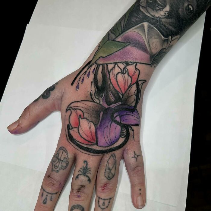Hand with a vibrant nature tattoo featuring flowers, showcasing the human-earth bond.