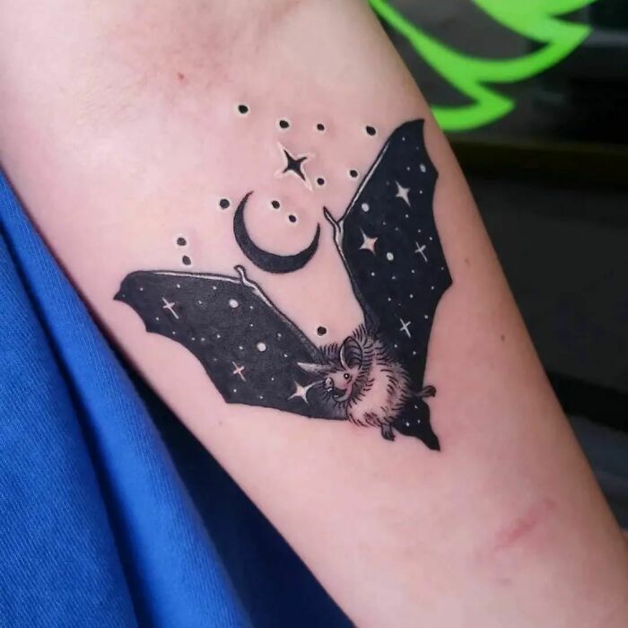 Nature tattoo of a bat with stars and a crescent moon on an arm, symbolizing the wonders of Mother Earth.