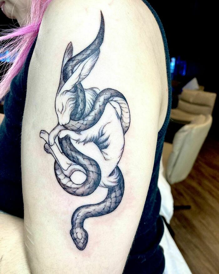 Tattoo of a mythical creature blending a rabbit and snake on someone's upper arm, celebrating nature's wonders.