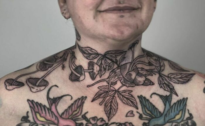 Neck and chest nature tattoo featuring leaves and mushrooms, emphasizing human-earth bond.