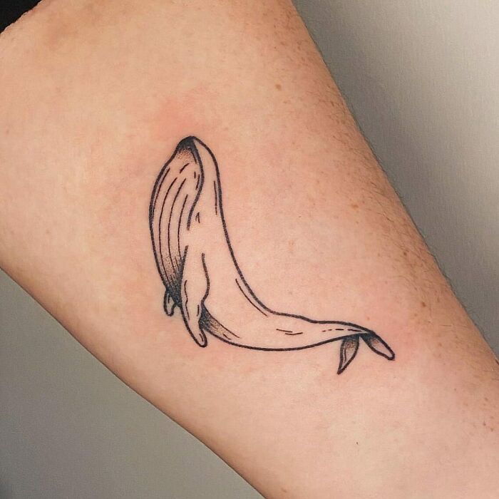 Minimalist whale nature tattoo representing a bond with Earth, inked on skin.