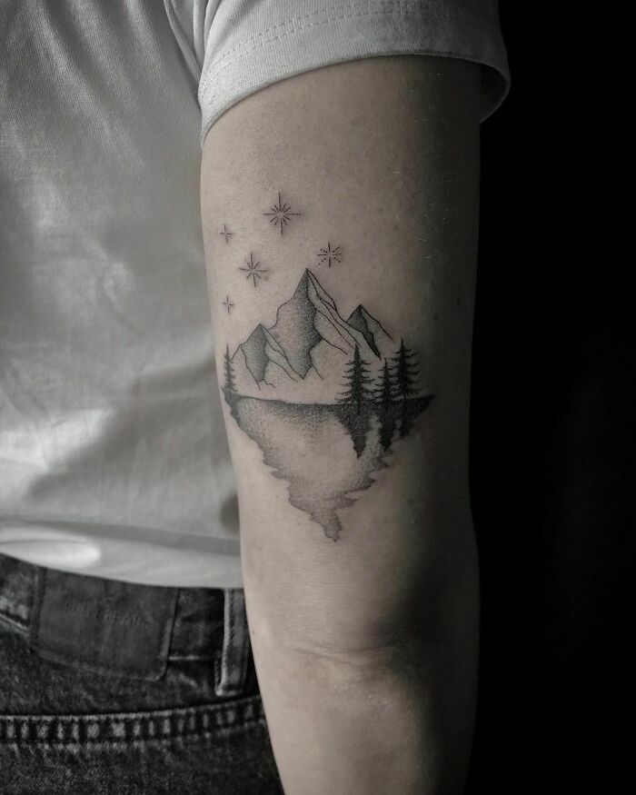 Nature tattoo of mountains, trees, and stars on an arm, celebrating the wonders of Mother Earth.