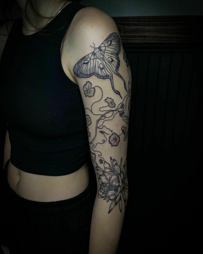 Nature tattoos featuring a moth, flowers, and vines on a person's arm, celebrating the wonders of Mother Earth.