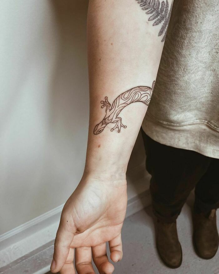 Nature tattoo of a stylized lizard on a person's forearm, showcasing earthy designs.