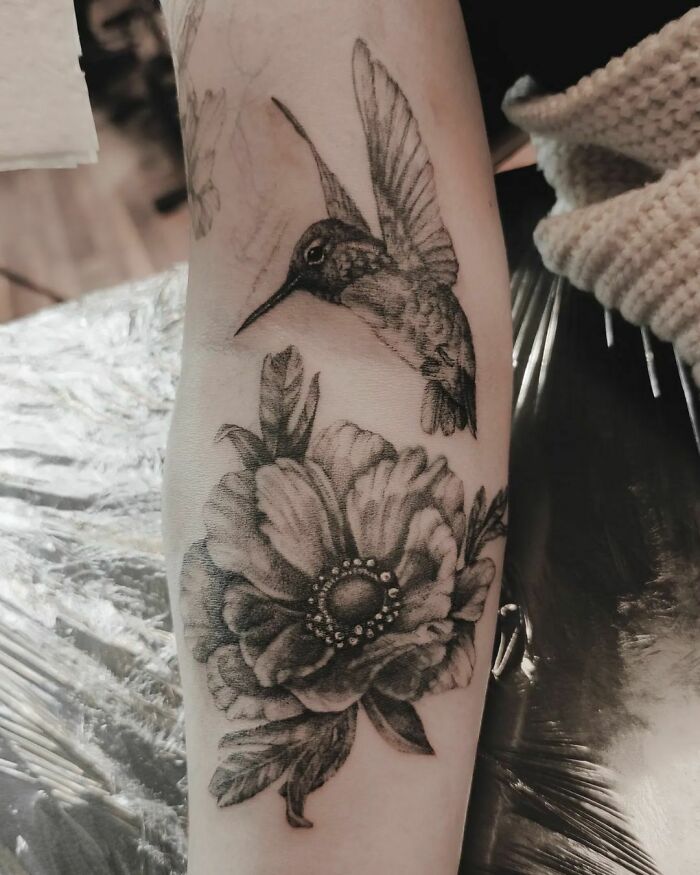 Nature tattoo featuring a detailed hummingbird and flower on a forearm, celebrating the beauty of Mother Earth.