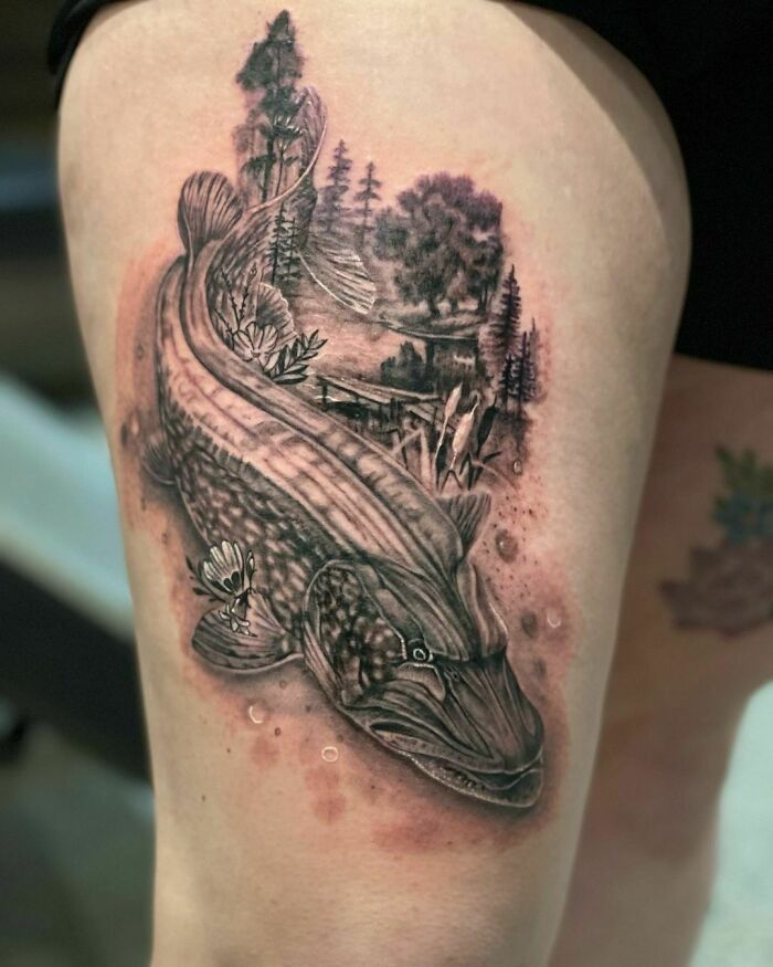 Nature tattoo featuring a detailed fish and forest scenery on a person's leg.