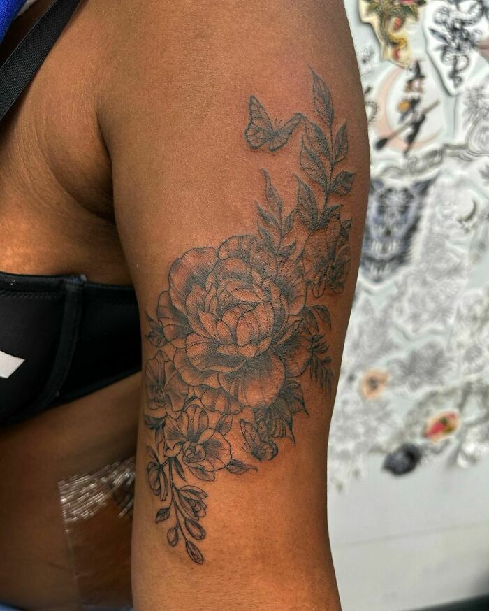 Floral nature tattoo on a person's arm with detailed leaves and a butterfly design.