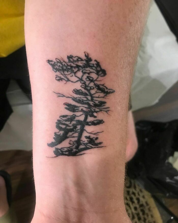 Black ink tree tattoo on arm, showcasing a nature-inspired design.
