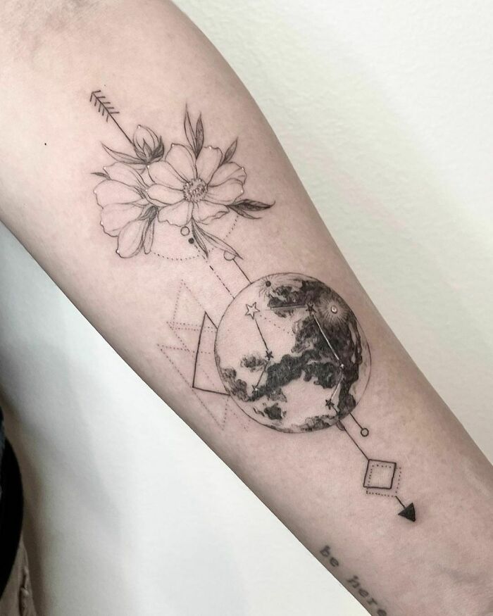 Nature tattoo featuring a flower and Earth design on the inner arm, signifying the human-earth bond.