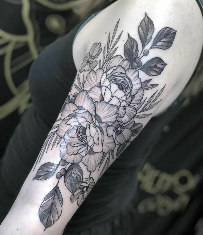 Floral nature tattoo on arm, featuring detailed flowers and leaves celebrating human-earth connection.