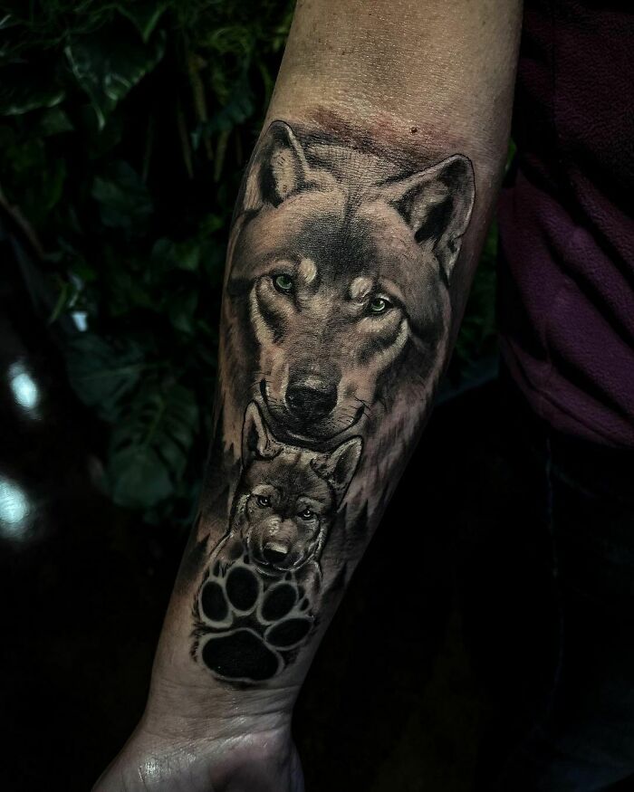 Wolf tattoo with paw print on forearm, embodying nature's wonders and the spirit of the wild.