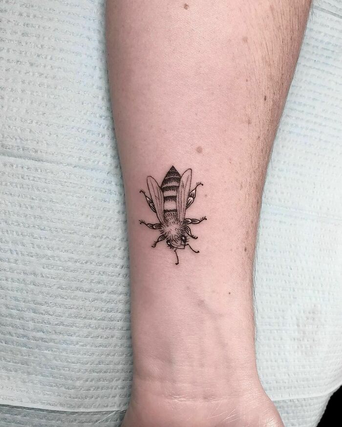 Detailed bee tattoo on forearm, showcasing a nature-inspired design for those with a wild side.