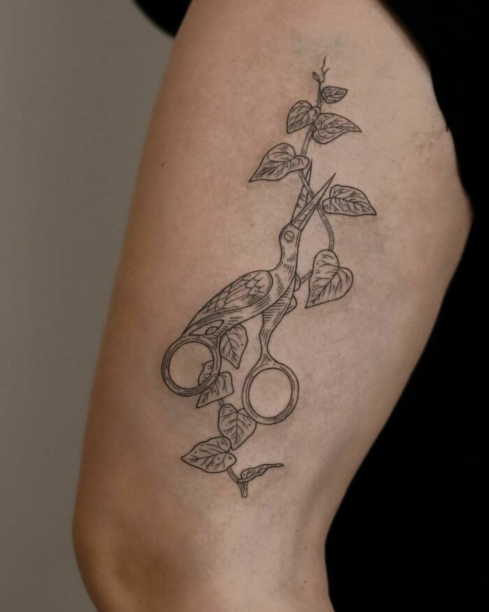 Nature tattoo of scissors and leaves on arm, celebrating the wonders of Mother Earth.