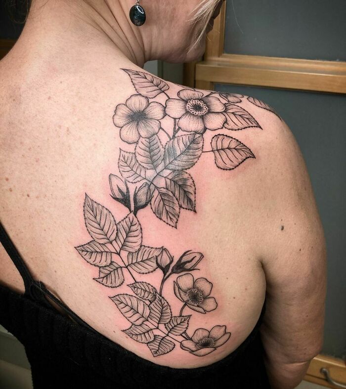Nature tattoo on shoulder featuring detailed flowers and leaves, symbolizing the human-earth bond.