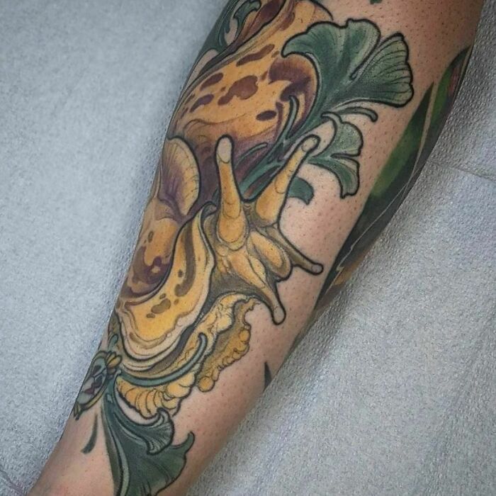 Colorful snail tattoo with leaves on an arm, showcasing a unique nature tattoo idea.