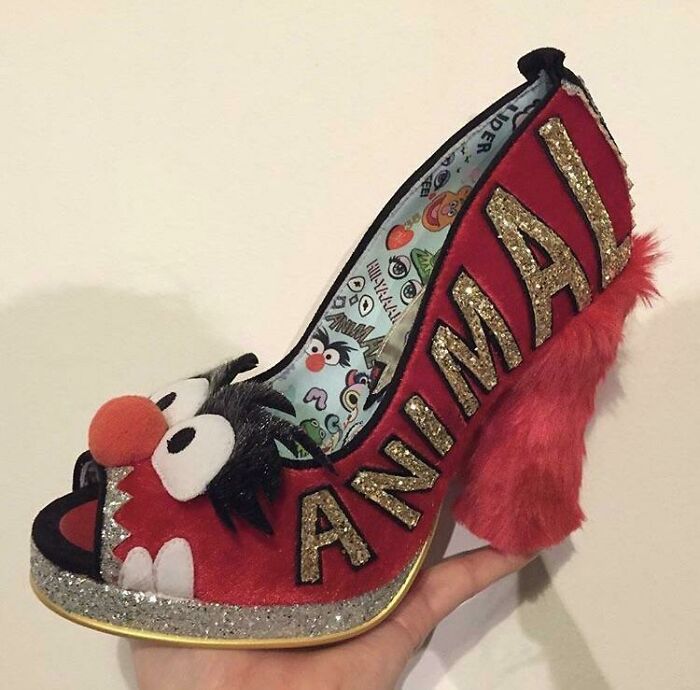 Weird shoe designed with fuzzy red fabric and cartoon character face, featuring the word "ANIMAL" in gold glitter.