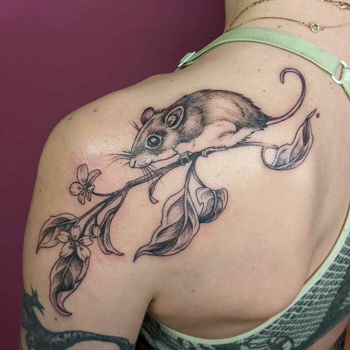 Nature tattoo of a mouse on a branch, inked on a person's shoulder, celebrating human-earth connection.