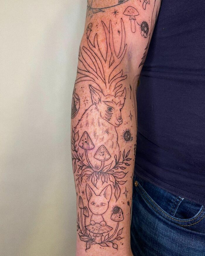 Tattoo of a mystical deer with antlers and forest elements on a person's forearm, showcasing nature-inspired ink art.