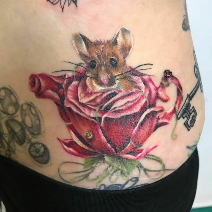 Nature tattoo featuring a mouse in a rose, with ladybugs and a key design.